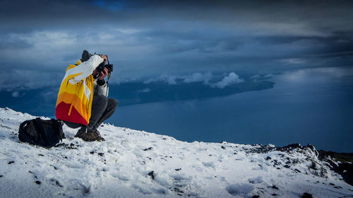 Person on snowcapped mountain against sky during winter