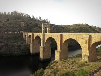 Arch bridge over river against clear sky