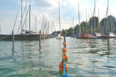 Sailboats moored in sea against sky
