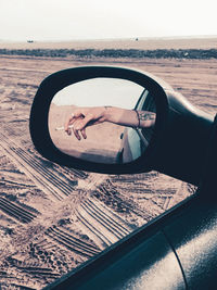 Reflection of man photographing on side-view mirror