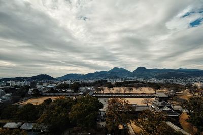 Kumamoto castle with cityscape against cloudy sky