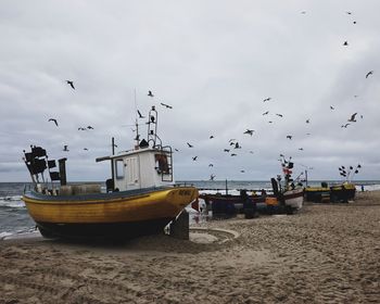 Boats moored at sea shore against sky