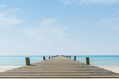 Empty pier over sea against sky