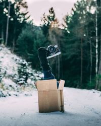 Cropped hand holding camera from cardboard box during winter