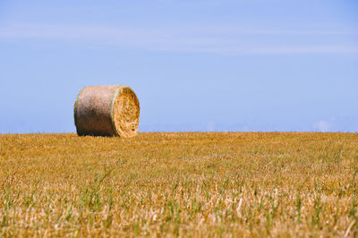 Hay bales on field against sky