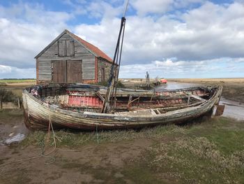 Abandoned ship moored on beach against sky