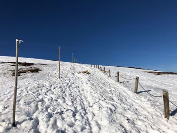 Snow covered land against clear blue sky