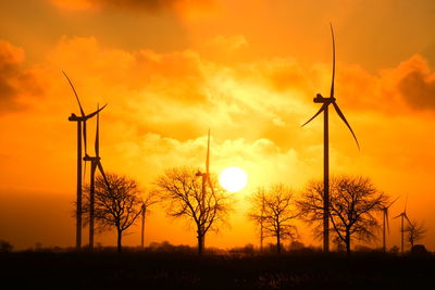 Low angle view of silhouette windmills against sky during sunset