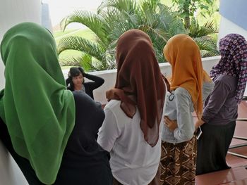 Rear view of friends standing on sofa