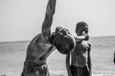 Full length of shirtless man at beach against sky