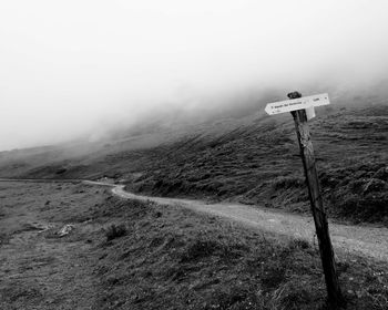 Road sign on land against sky