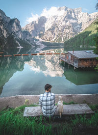 Man sitting by lake against mountains