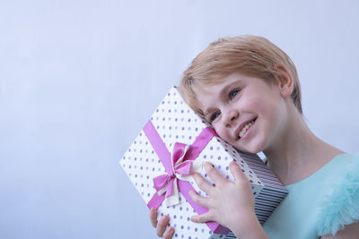 Portrait of young woman holding gift against blue background