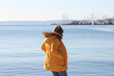 Rear view of woman standing by sea against sky