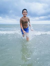 Portrait of young boy in sea against sky