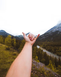 Midsection of person hand on mountain against sky