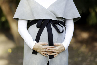 Midsection of pregnant woman standing on field