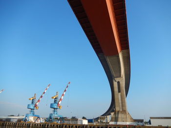 Low angle view of crane against clear blue sky