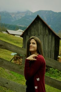 Portrait of beautiful young woman standing on wood against mountain
