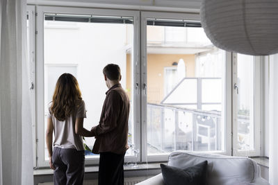 Couple looking through window while standing in new home