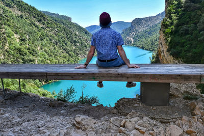 Rear view of man sitting on mountain looking at view