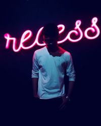 Full length of young man standing against illuminated light painting