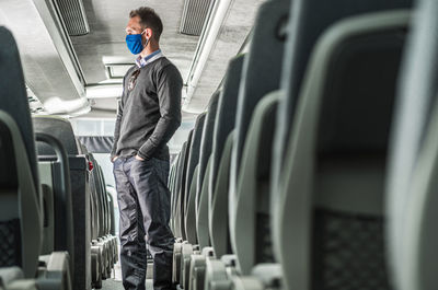 Man with hands in pockets standing in bus