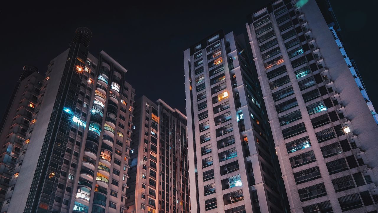 LOW ANGLE VIEW OF ILLUMINATED BUILDINGS AGAINST SKY AT NIGHT