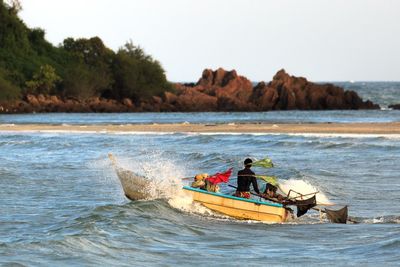 Rear view of fisherman sailing boat in sea against clear sky