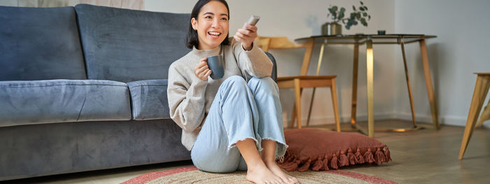 Portrait of young woman sitting on sofa at home