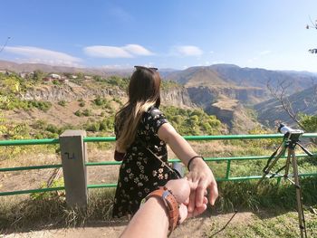 Cropped image of man holding woman hands on mountain