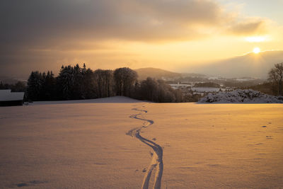 Scenic view of snow covered landscape against sky during sunset