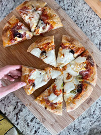 High angle view of hand holding pizza on table