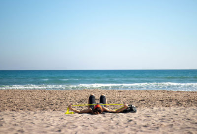 Adult woman exercising with rubber bands on the beach lying down on the beach