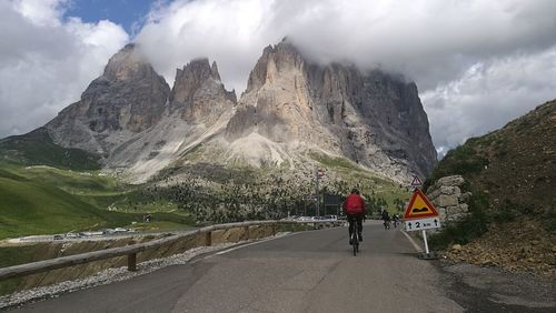 Man riding bicycle on road against mountains