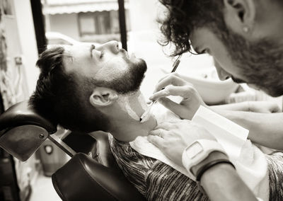 Barber shaving beard of customer at salon