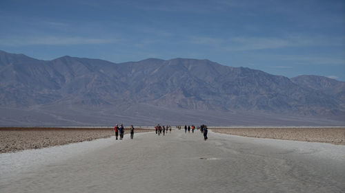 People walking on road leading towards mountains