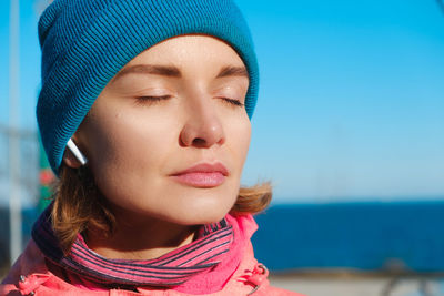 Close-up portrait of woman in hat against sea