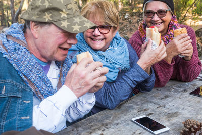 Senior friends having food at table in forest