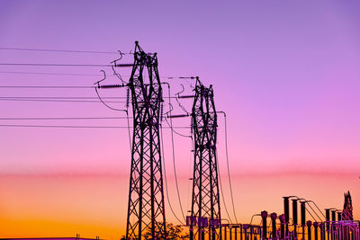 Low angle view of electricity pylon against sky during sunset