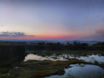 Scenic view of lake against sky at sunset