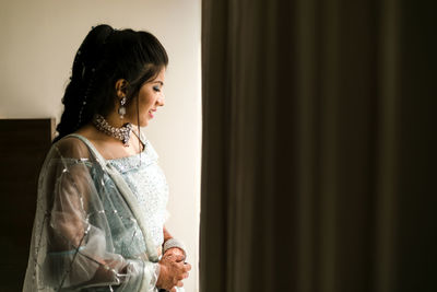 Side view of a young woman looking through window