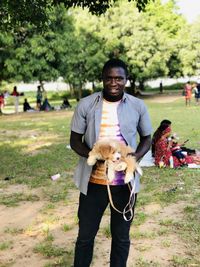 Portrait of man holding dog standing at park