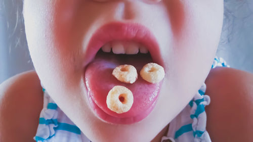 Close-up of girl with snacks on tongue