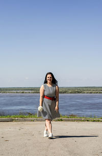 Young woman holding flowers on riverside background