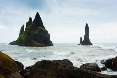 Rock formation on beach against sky