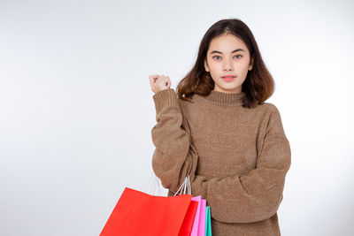 Portrait of young woman standing against white background