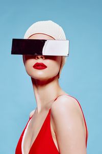 Midsection of woman wearing hat against blue background