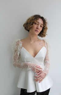 Young woman looking away while standing against white background