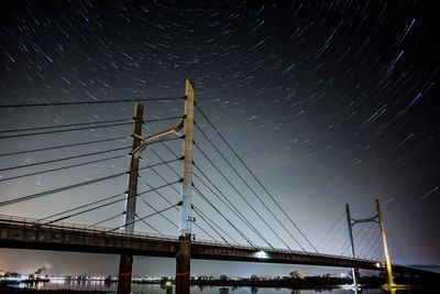 Low angle view of suspension bridge against sky at night